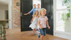 family arriving home through open doorway 2026 01 09 11 00 34 utc
